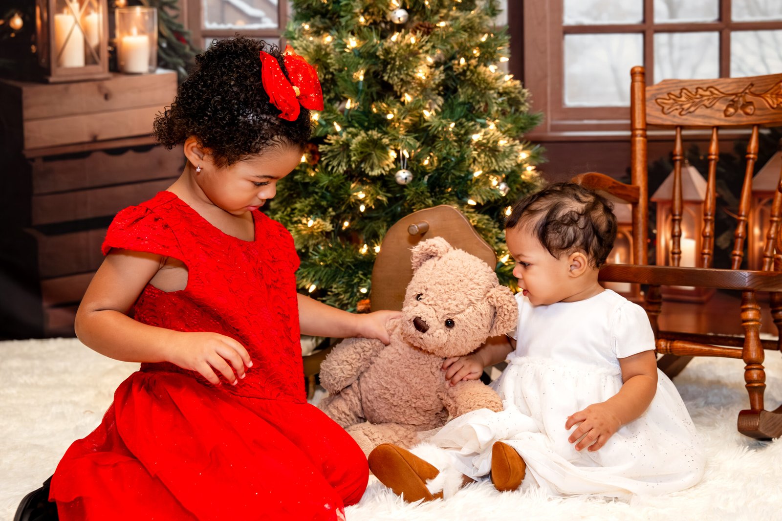 Two younger sisters playing together with a teddy bear.