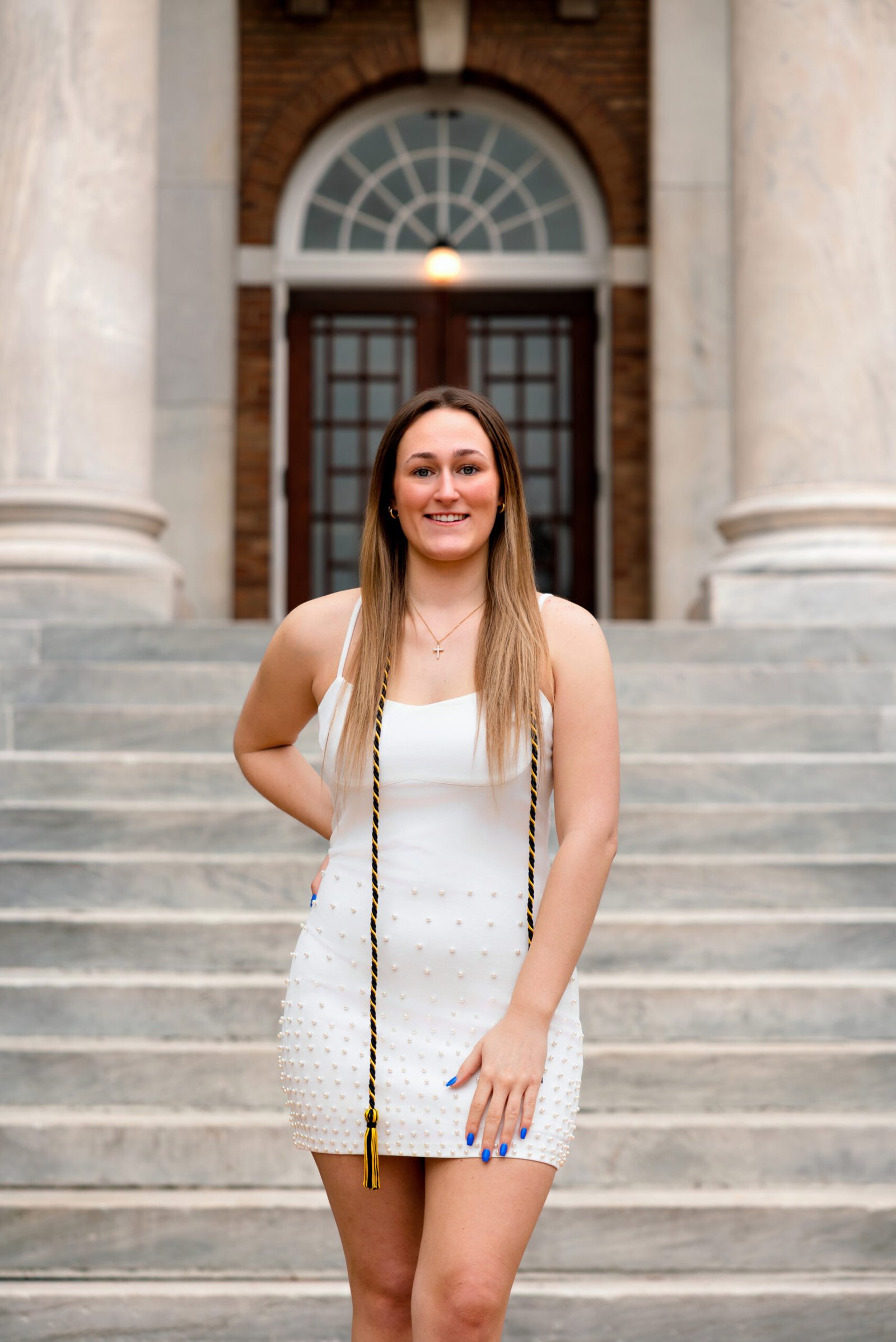 Evoto Graduation student standing infront of college building with her grad cap and cords.