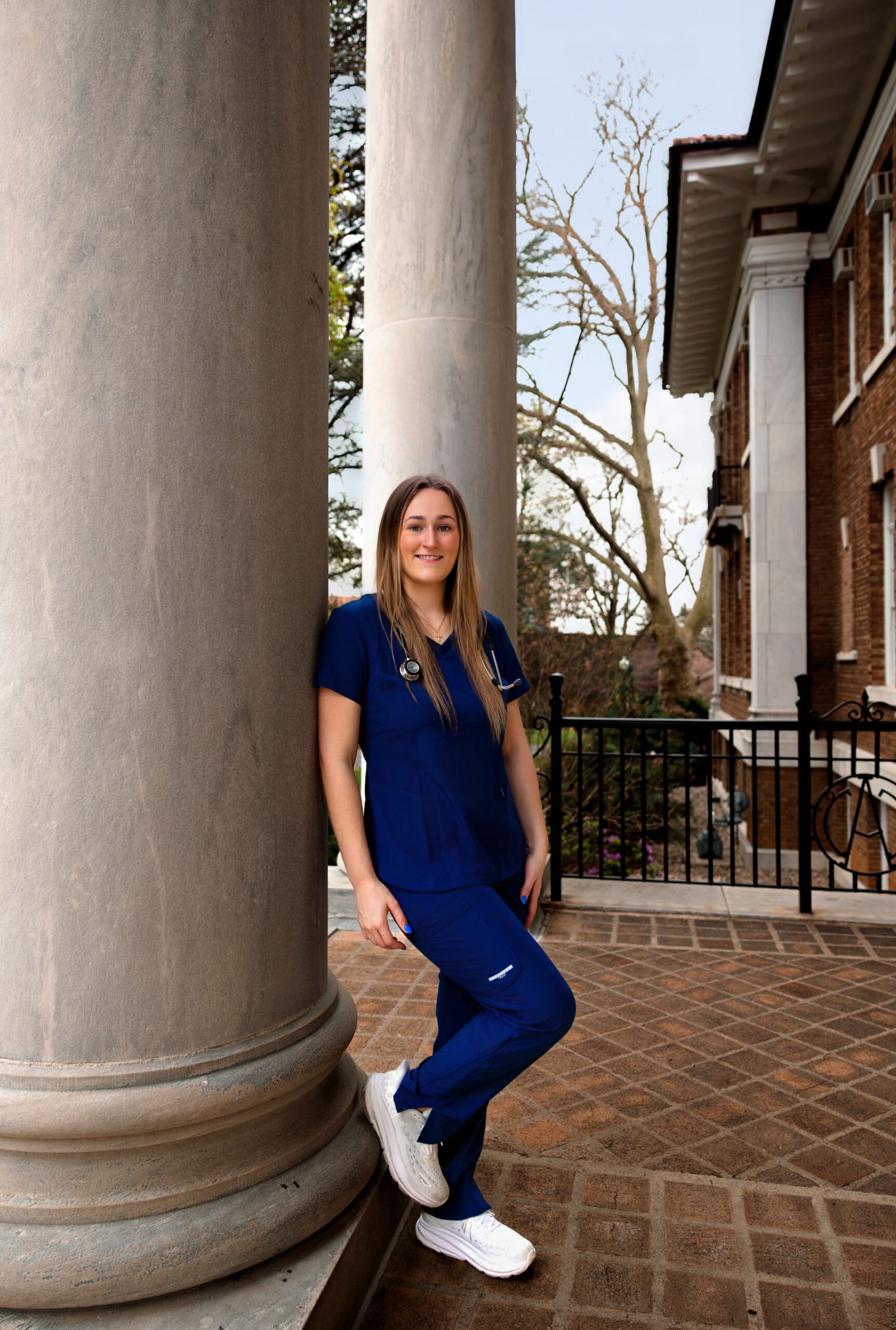 Evoto Nursing student leaning against a pole in her scrubs.