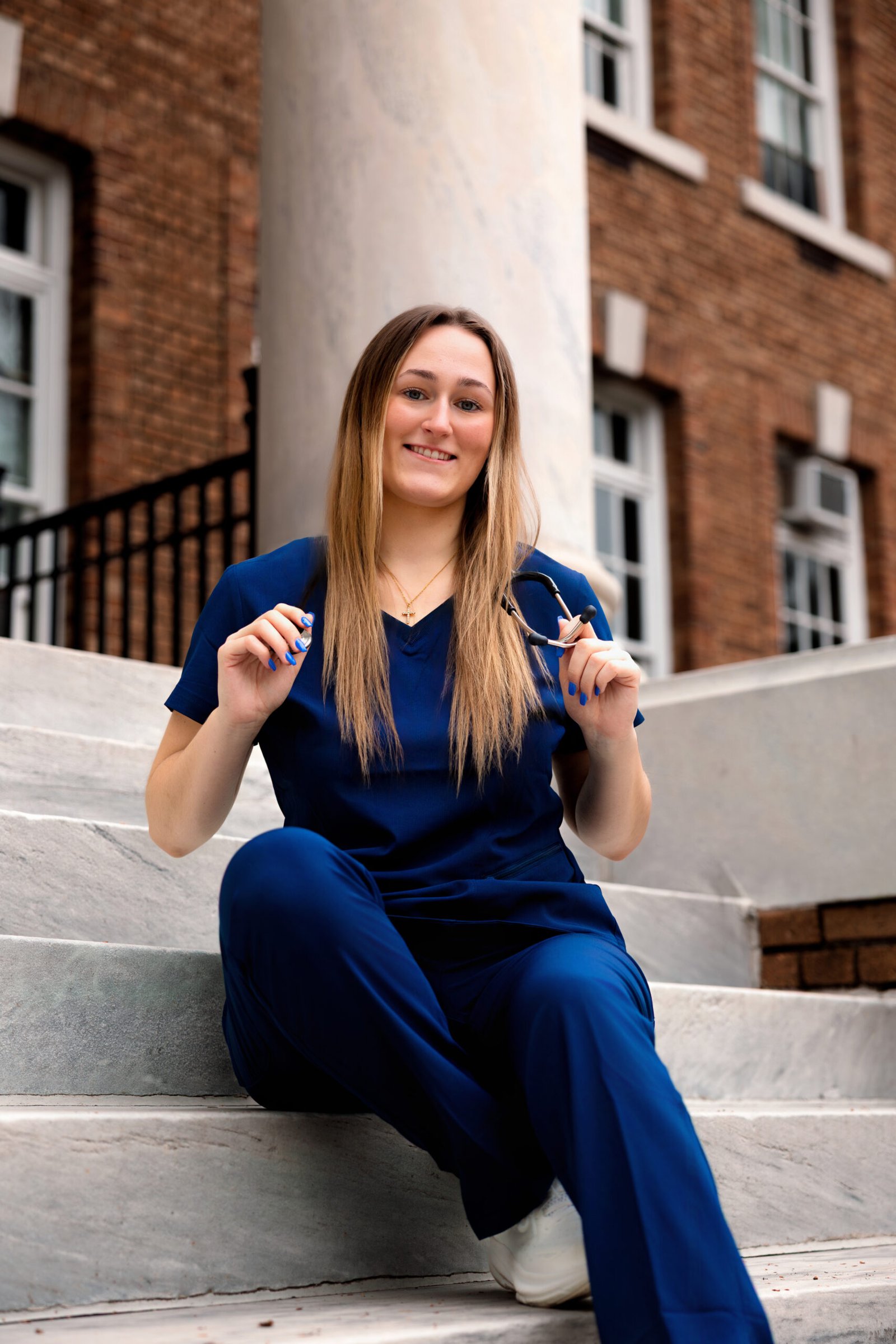 Evoto Nursing student sitting on the steps with her stethoscope.