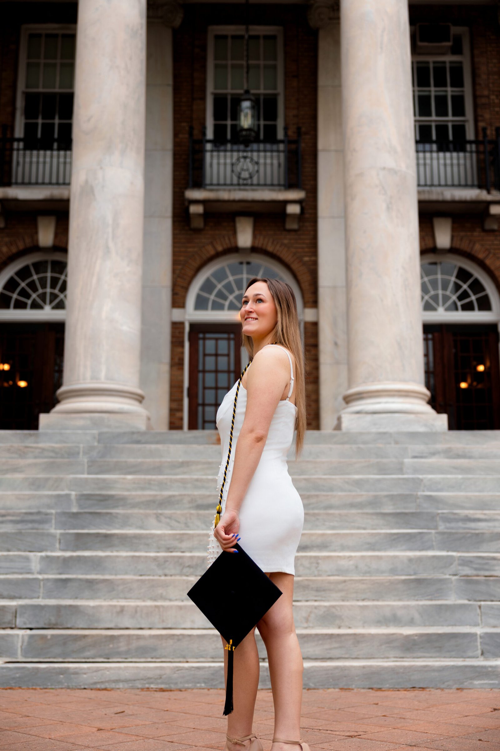Evoto Graduation student standing infront of college building with her grad cap and cords.