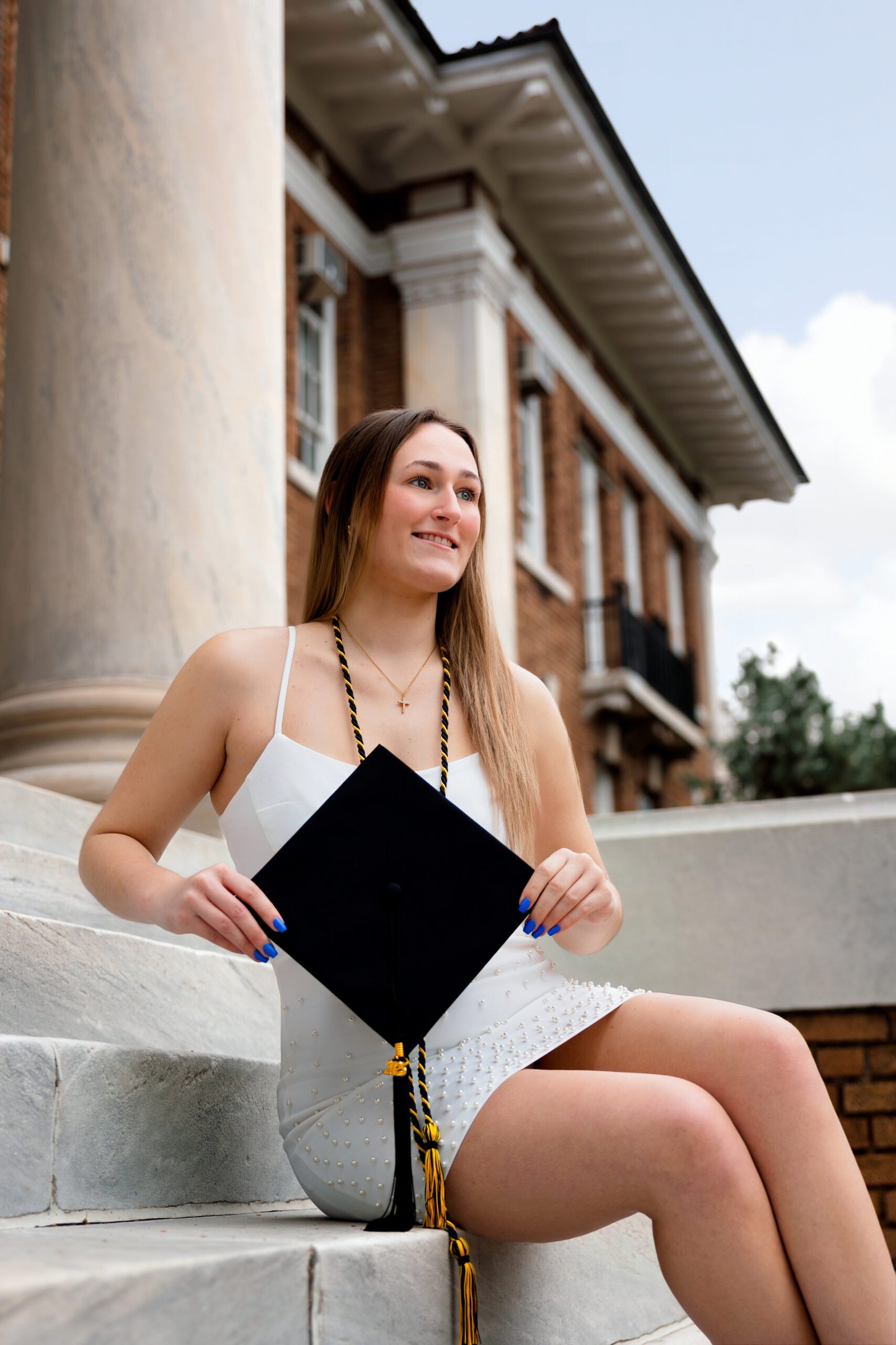 Evoto Grad student sitting on the steps with her graduation cap.