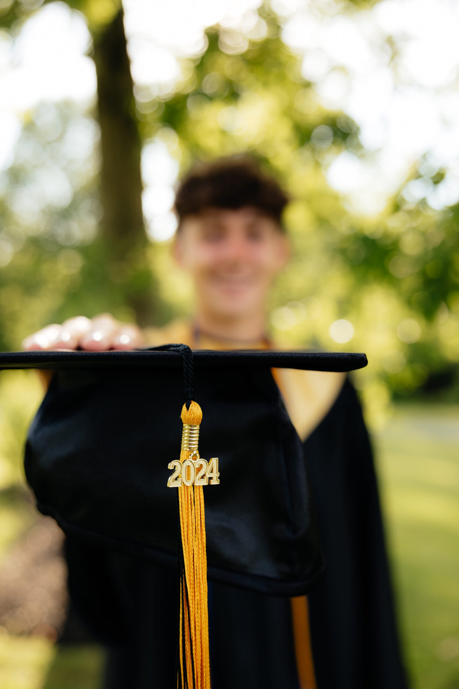 zach_highschoolgrad Outdoor portrait close up of a high school senior holding his graduation cap.